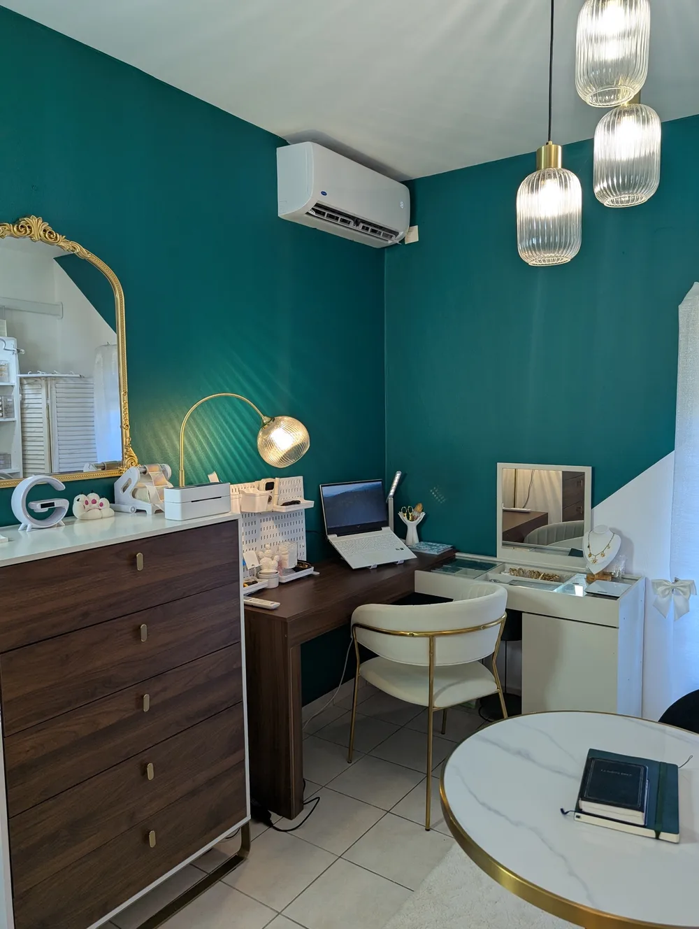 Bureau de création de Lysaia, marque de bijoux en Guyane, murs vert émeraude, présentoirs de bijoux et miroir doré